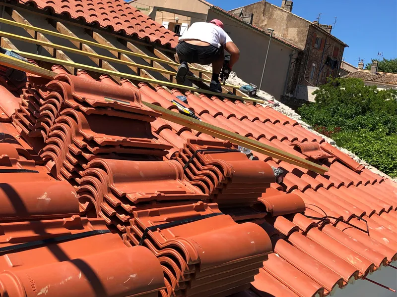 Artisan couvreur posant des tuiles sur un toit dans le Var
