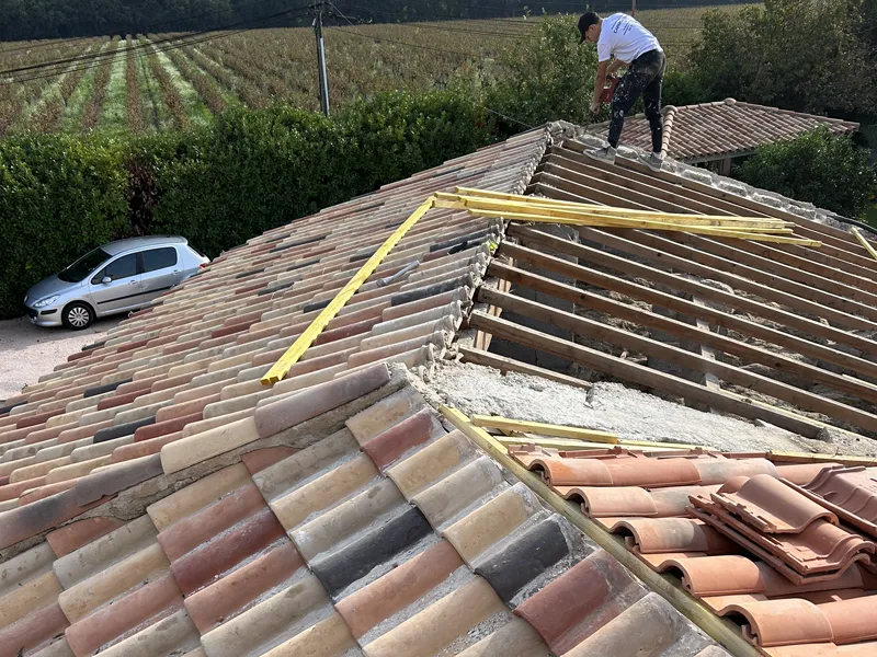Toiture en cours de dépose avec charpente apparente et tuiles empilées